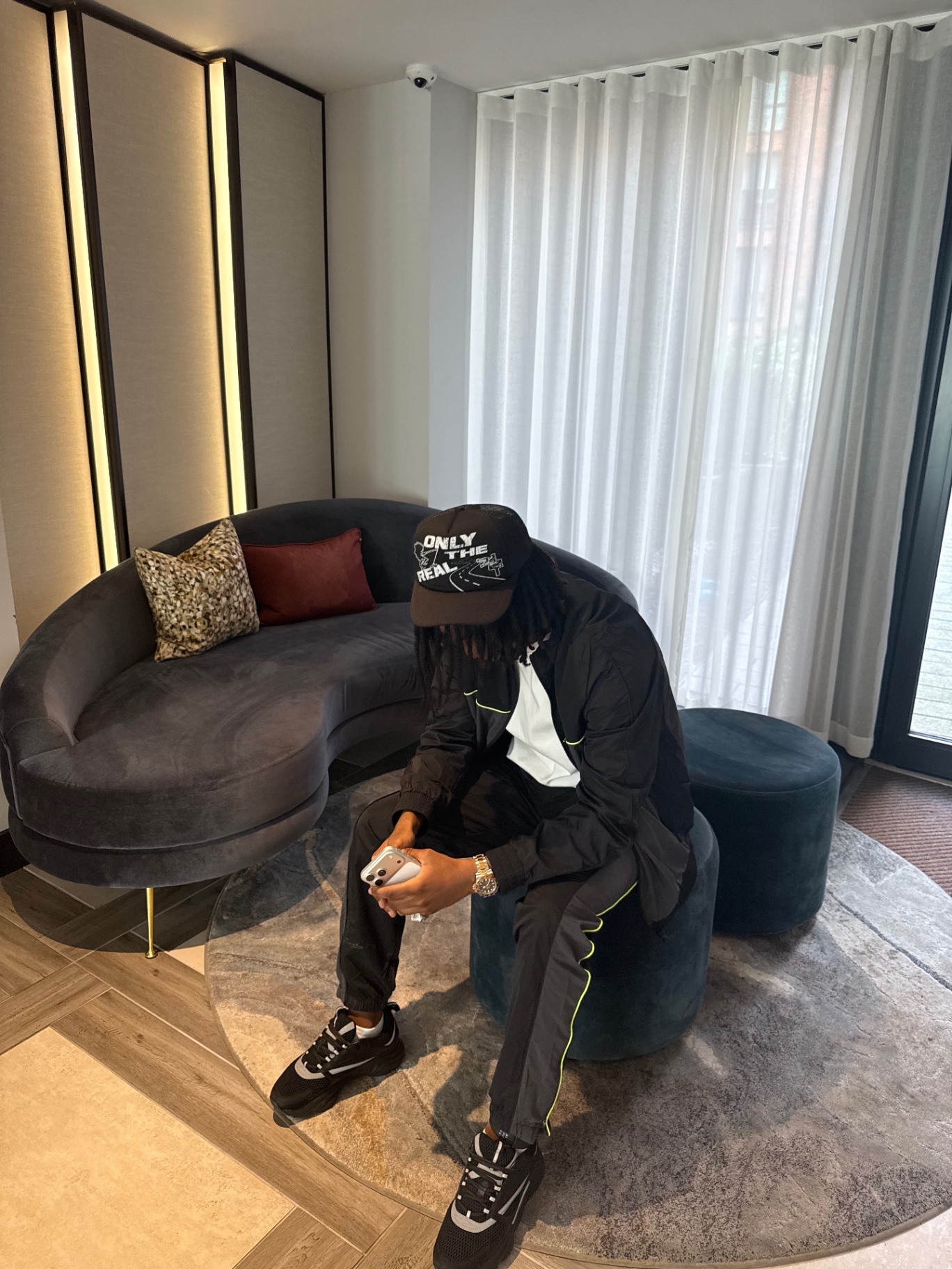 Only The Real campaign image with model seated indoors wearing the cap.